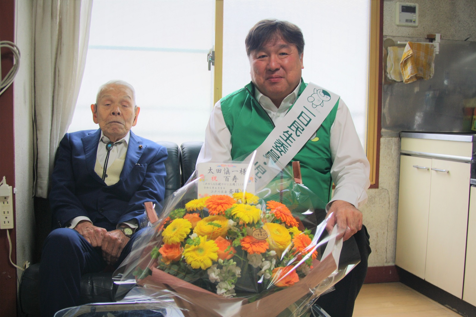 100歳になった区民男性と一緒に記念写真を撮る区長