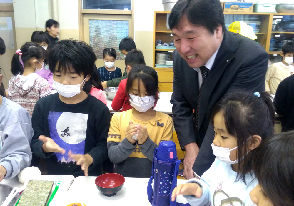 画像：おにぎりを作る児童を見守る斉藤区長1