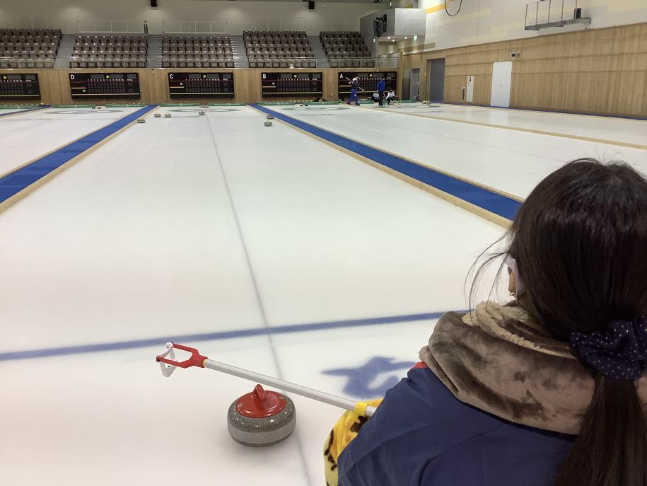 花岡選手の後ろ姿とカーリング場