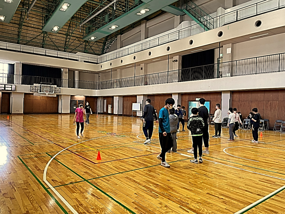 2グループに分かれ、床に置かれたフープの中を順番に歩いていく参加者たち