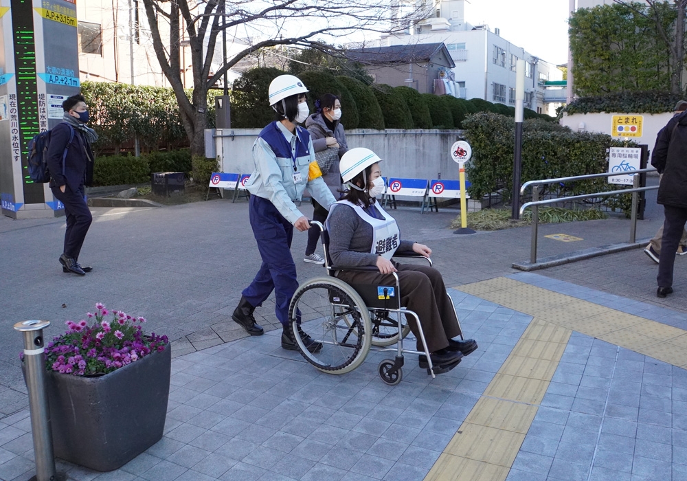 写真：車いす利用者役の職員と介助者役の職員