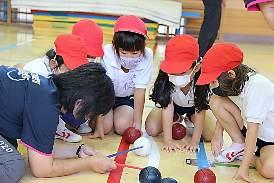 どちらのボールが近いか審判と確認する子ども