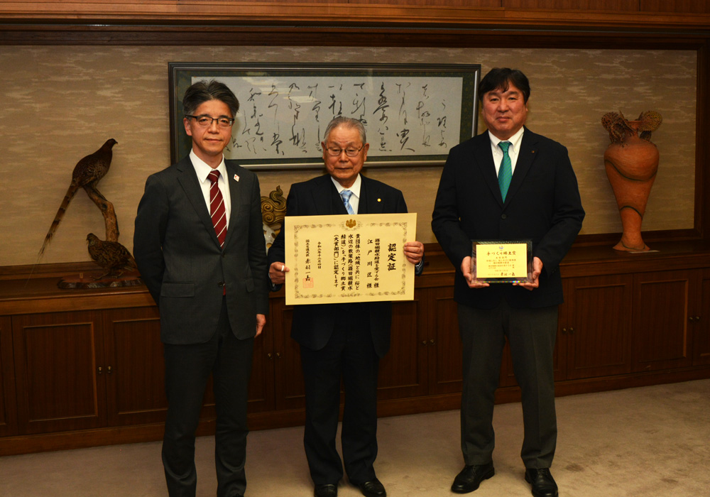 写真：認定証を手に、篠田堀親水緑道を愛する会の皆さんと斉藤区長