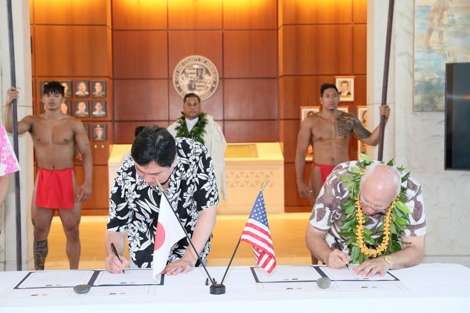 姉妹都市盟約の締結式で書類にサインするそれぞれの市（区）長
