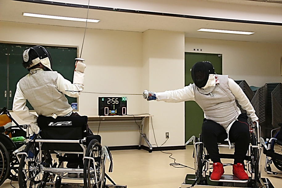 サーベルを伸ばし攻めたてる参加者と体を引いてかわそうとする相手