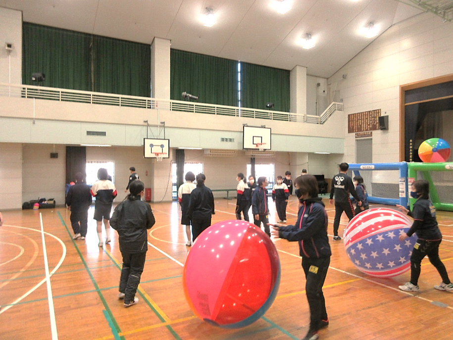 ビニールの大玉を転がして体操をする参加者たち