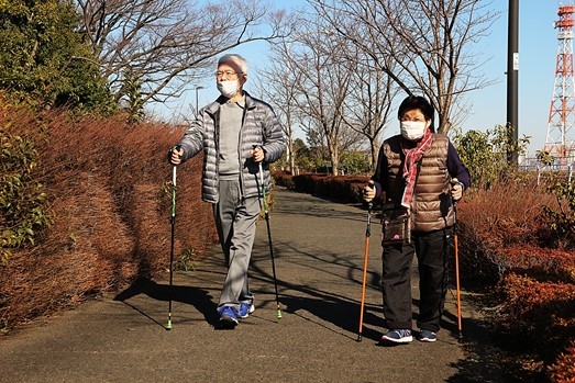 ポールを使って歩道を歩く男性と女性の参加者