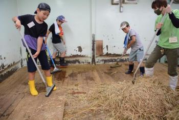 サマースクールで動物小屋の清掃をする小学生たち