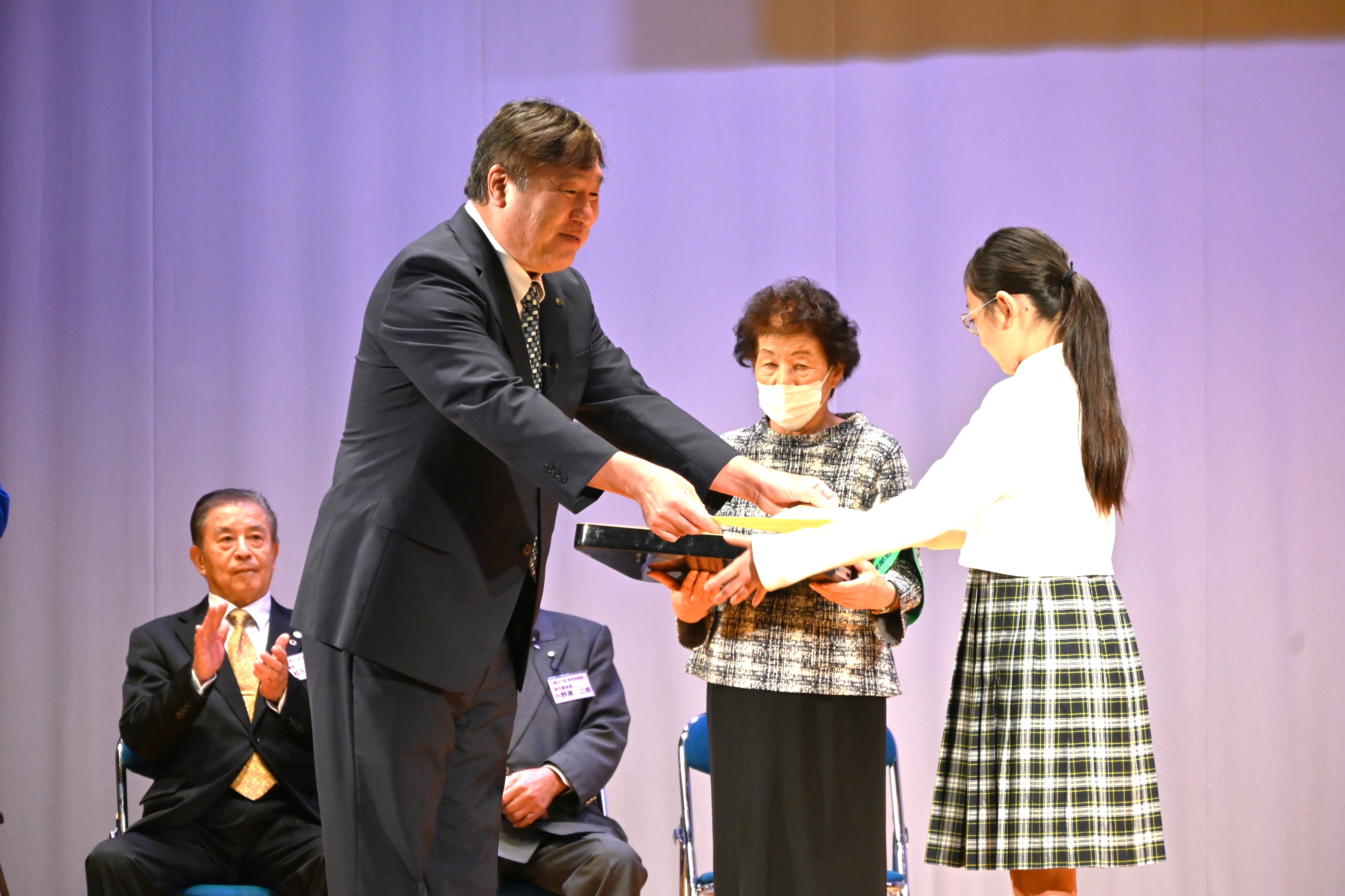 表彰式で賞状を渡す区長