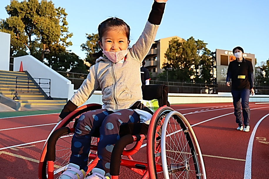 笑顔で競技用車いすに乗る少女