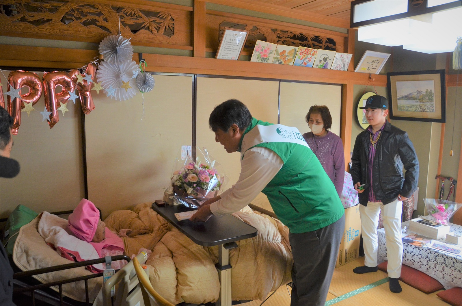 100歳のお誕生日を迎えた区民の家を訪問し、花束を渡す区長