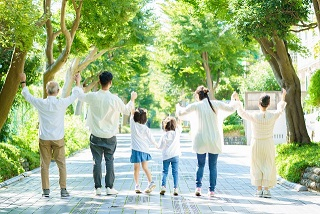 緑豊かな道を歩く家族の後ろ姿