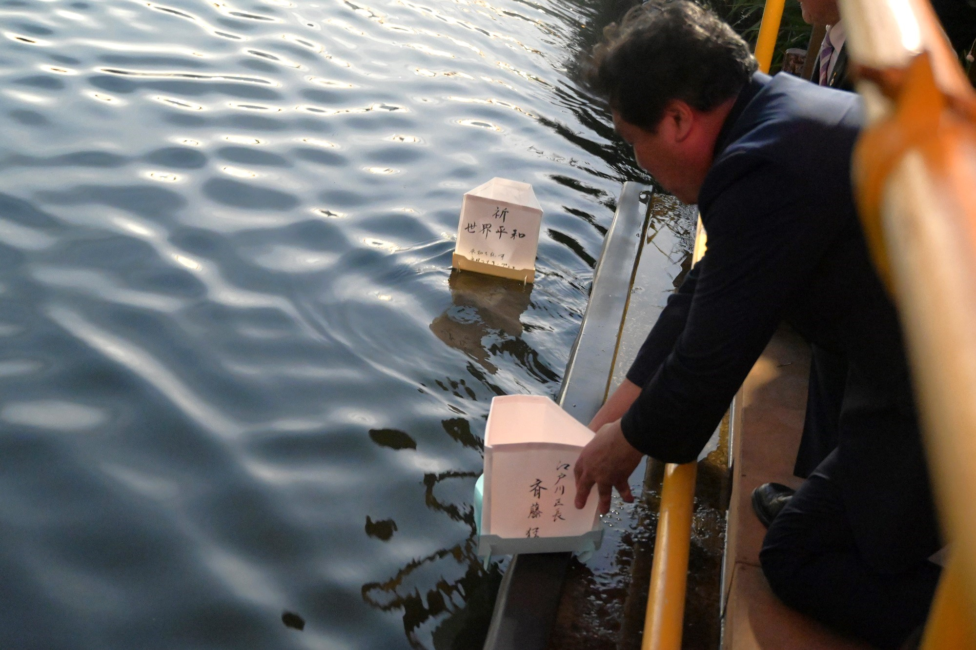 川面へ灯籠を浮かべる区長