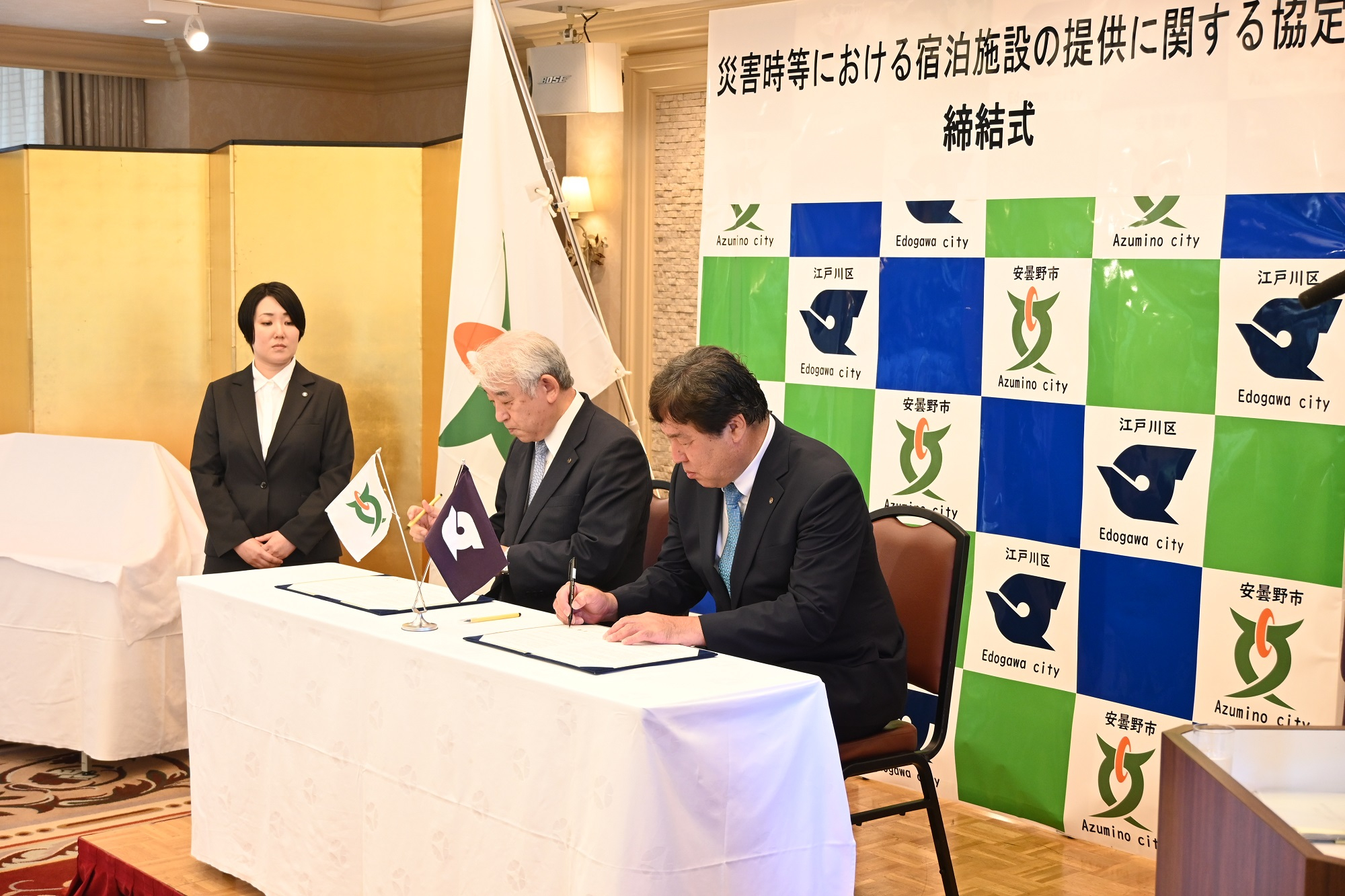 友好都市盟約締結式で書類にサインする区長
