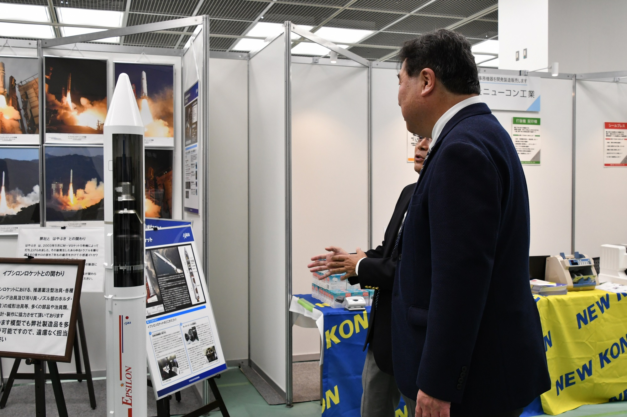 企業・団体の出展ブースで担当者から説明を受ける区長
