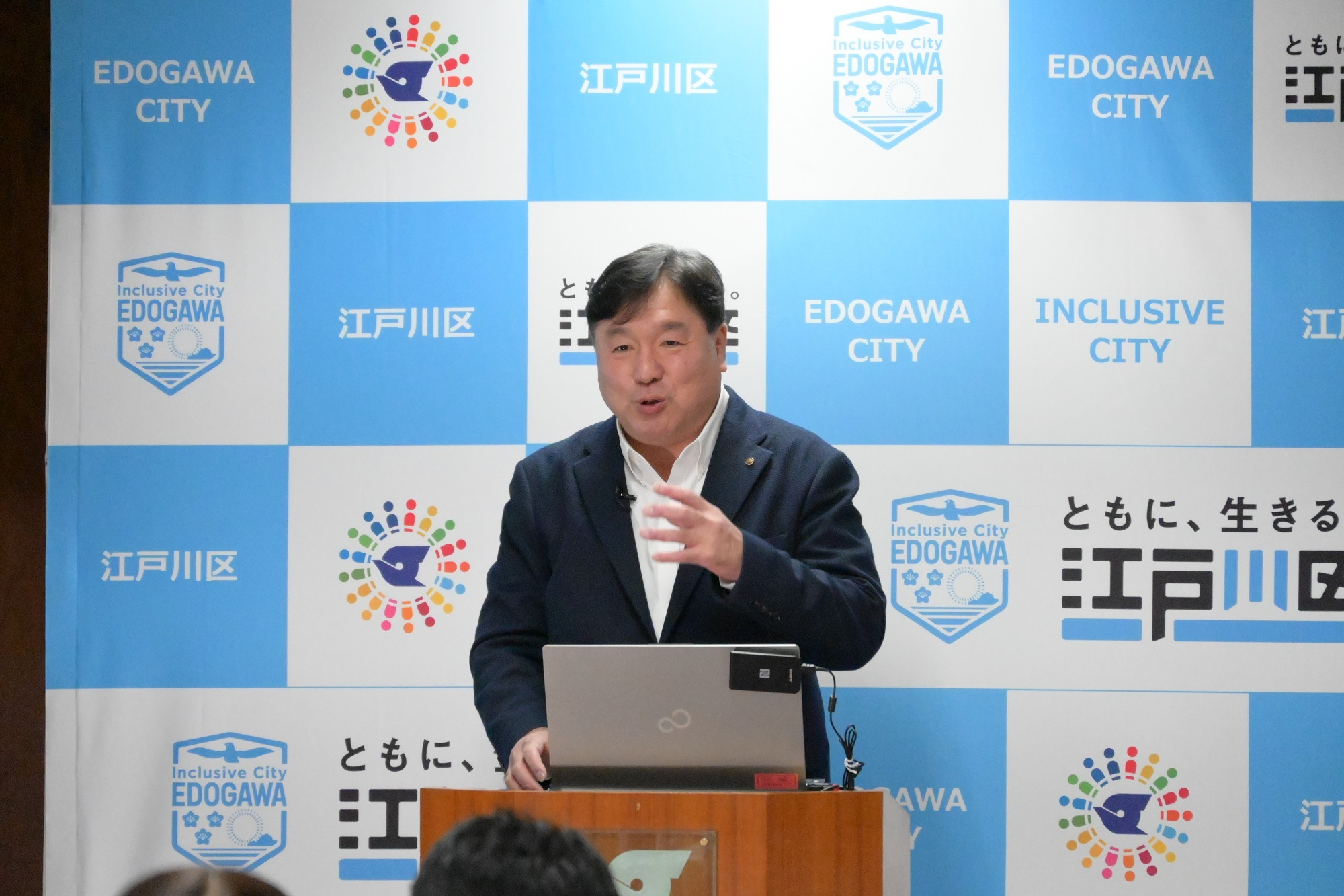 記者へむけて説明する区長