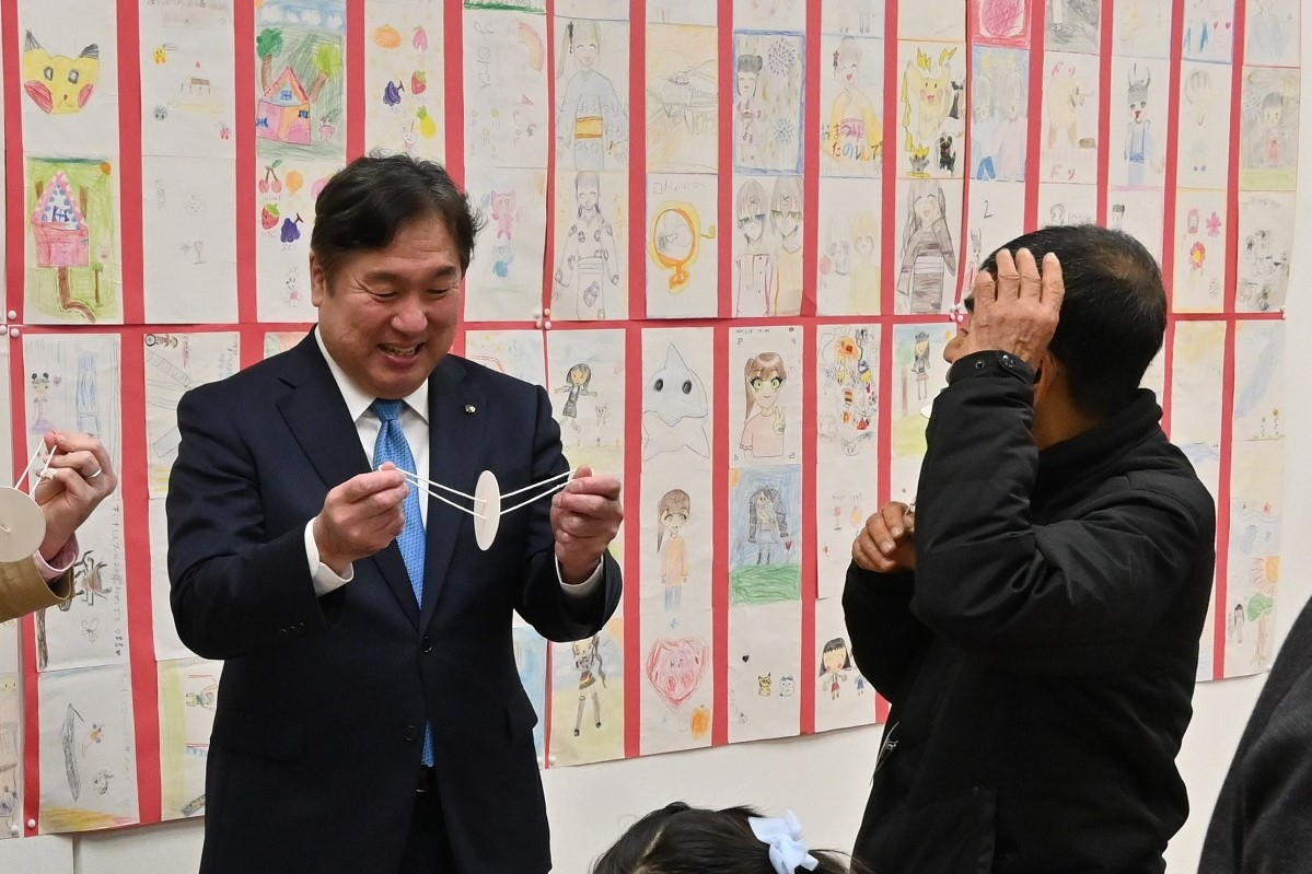 展示品を触って微笑む区長