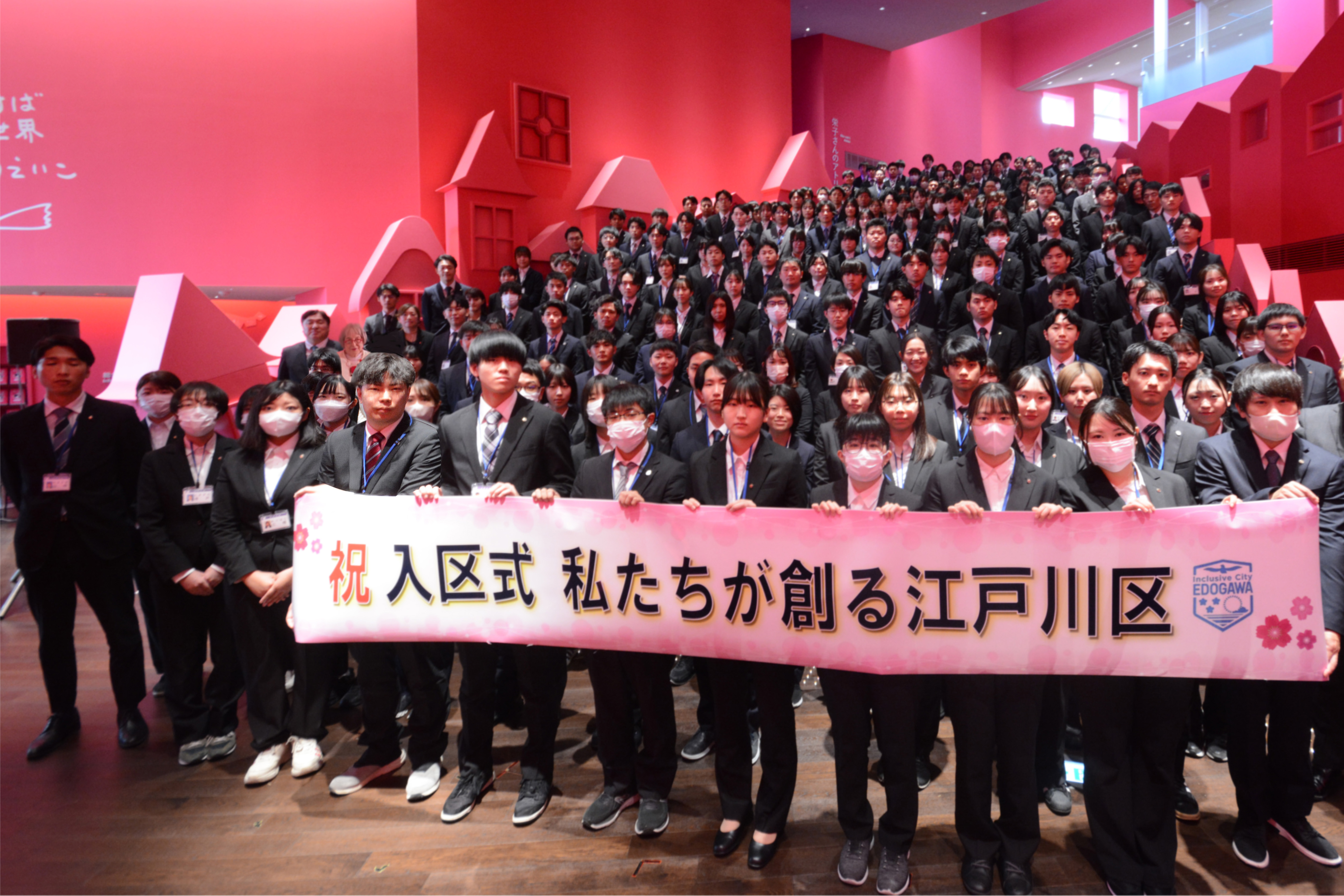 「私たちが創る江戸川区」という横断幕を持ち並ぶ新入職員