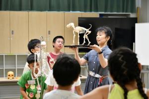 恐竜の骨格標本を見せる佐藤さん