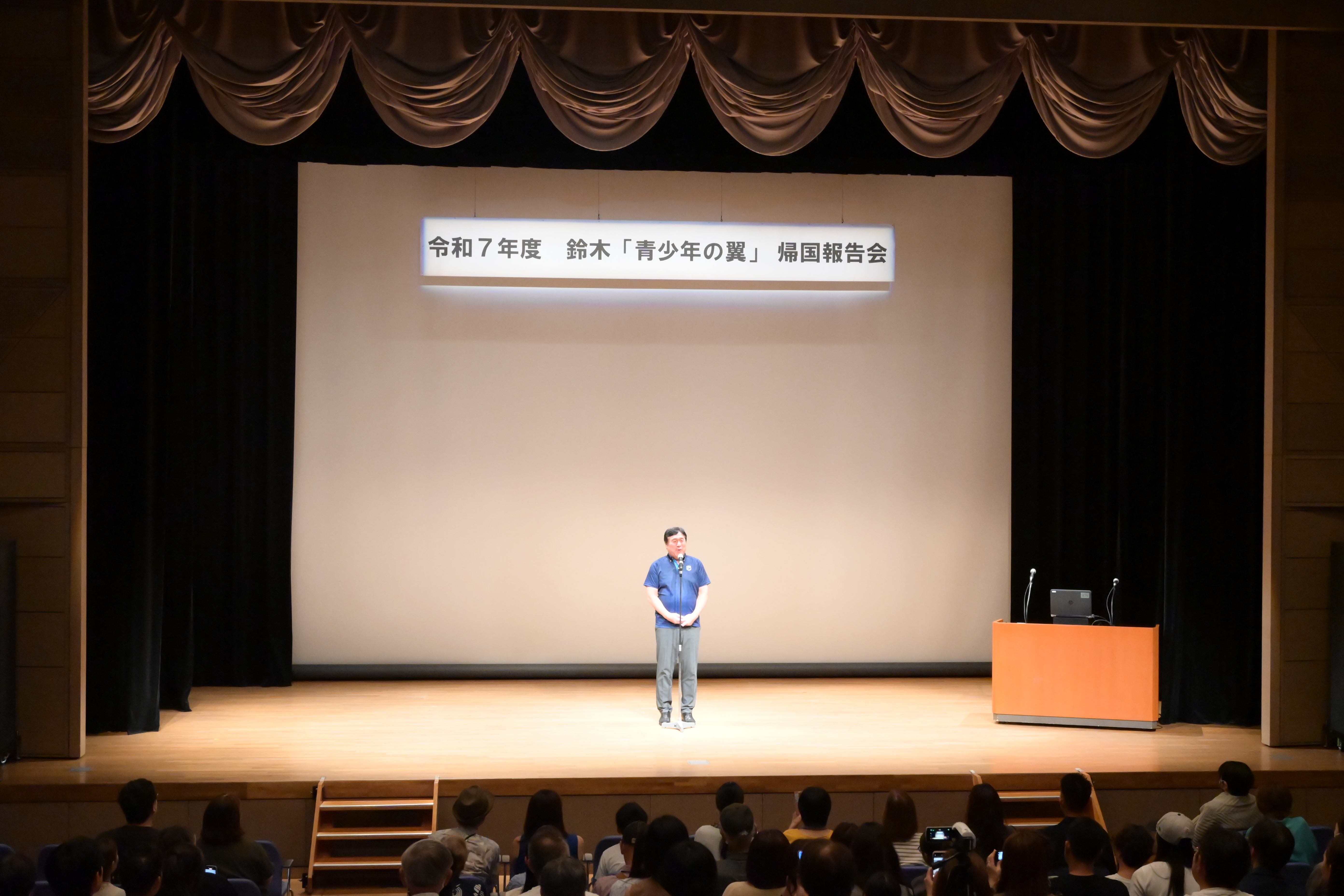 鈴木「青少年の翼」帰国報告会で話す斉藤区長