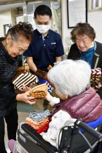 入所者に靴下カバーを渡す吉田さん